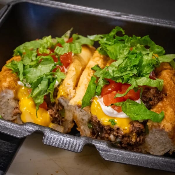 Two loaded southern-style hot dogs with ground beef, cheese, lettuce, tomatoes, and sour cream.