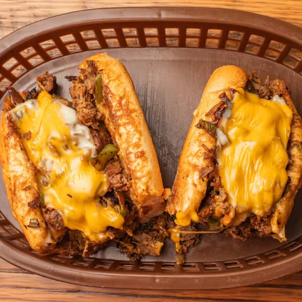 Two cheesy steak and pepper sandwiches in a brown basket, JD's Cafe.